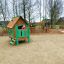 Drewniany domek dla dzieci Britty z drabinką i zjeżdżalnią na placu zabaw.