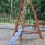 Drewniana konstrukcja wspinaczkowa Tipi I z zjeżdżalnią dla dzieci na placu zabaw.