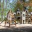 Plac zabaw Tipi I z drewnianą wieżą i zjeżdżalnią, umieszczony w parku.