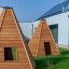 Drewniane domki w kształcie wigwamu dla dzieci na trawniku.