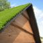 Drewniany domek ze sztuczną trawą na dachu w naturalnym otoczeniu.