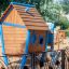 drewniany domek z niebieskimi elementami na placu zabaw dla dzieci