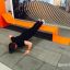 Mężczyzna ćwiczy na pomarańczowym urządzeniu do fitness na zewnątrz Fitness Serpentyna II.