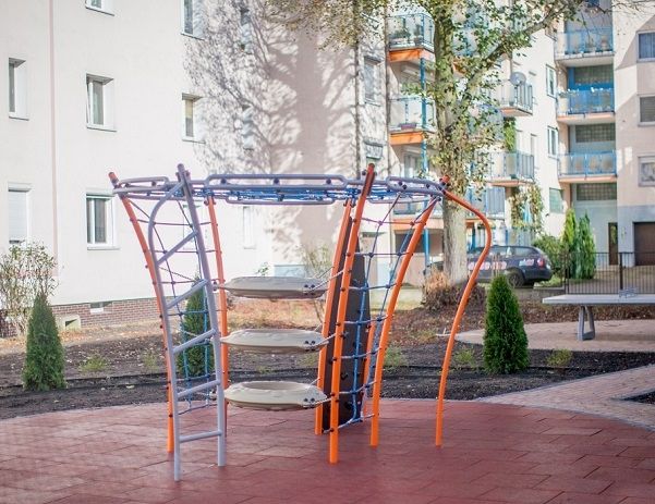 Pomarańczowo-niebieski sprzęt do ćwiczeń na placu zabaw z gumowymi platformami.