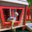chłopiec bawiący się w drewnianej kolorowej chatce na placu zabaw
