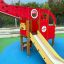 Plac zabaw dla dzieci z czerwonym helikopterem i żółtą zjeżdżalnią w parku.