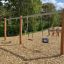 Huśtawka podwójna Robinia Swing Nature 1+2 na placu zabaw w otoczeniu przyrody.