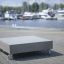 InsideOut Concrete Stolik z betonu na kółkach na tle mariny z jachtami.