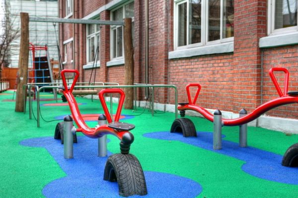 Plac zabaw z czerwonymi huśtawkami Wetpour 60 na kolorowej, bezpiecznej nawierzchni.