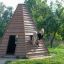 Drewniany wigwam z dziećmi bawiącymi się na zewnątrz w ogrodzie.