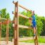 Chłopiec wspina się na drewnianą drabinkę wysoką na placu zabaw.