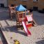 Centrum zabaw ze zjeżdżalnią, drabinką metalową usadowiony na piasku jako  powierzchna bezpieczna.