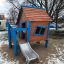 niebieski domek z drewna ze zjeżdżalnią na ośnieżonym placu zabaw