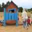 dzieci bawiące się w drewnianym kolorowym domku na placu zabaw