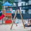 Dzieci bawiące się na placu zabaw z huśtawką i zjeżdżalnią w modelu Ptasie Gniazdo z Wieżą Logo (BNS
