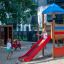 Dzieci bawiące się na kolorowym placu zabaw z drewnianym Ptasie Gniazdo z Wieżą Logo.